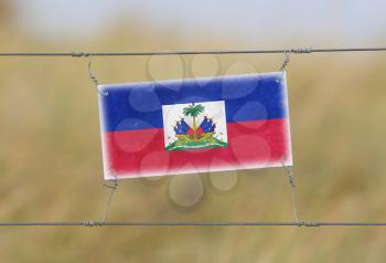 Border fence - Old plastic sign with a flag - Haiti