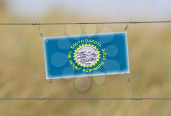 Border fence - Old plastic sign with a flag - South Dakota