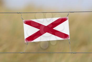 Border fence - Old plastic sign with a flag - Alabama