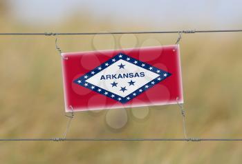 Border fence - Old plastic sign with a flag - Arkansas