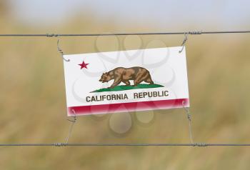 Border fence - Old plastic sign with a flag - California