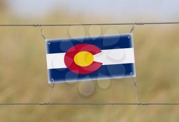 Border fence - Old plastic sign with a flag - Colorado