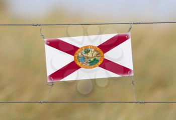 Border fence - Old plastic sign with a flag - Florida