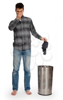 Young man putting dirty socks in a laundry basket, isolated on white