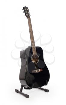 Black acoustic guitar on stand, isolated on a white background