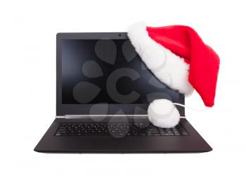 Modern open laptop with red santa claus hat put on lcd corner, isolated on white