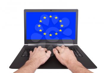 Hands working on laptop showing on the screen the flag of European Union