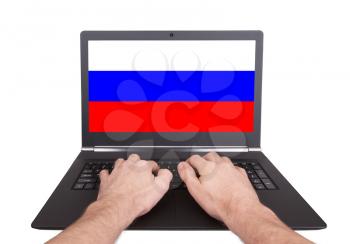 Hands working on laptop showing on the screen the flag of Russia