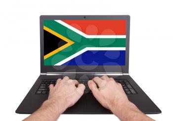 Hands working on laptop showing on the screen the flag of South Africa