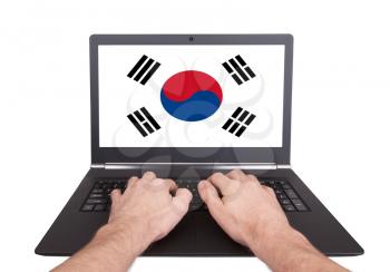 Hands working on laptop showing on the screen the flag of South Korea