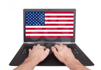 Hands working on laptop showing on the screen the flag of the USA