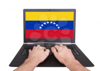 Hands working on laptop showing on the screen the flag of Venezuela