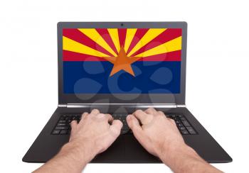 Hands working on laptop showing on the screen the flag of Arizona
