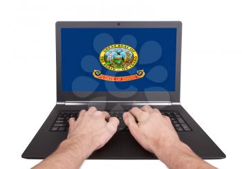 Hands working on laptop showing on the screen the flag of Idaho