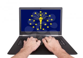 Hands working on laptop showing on the screen the flag of Indiana