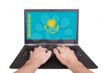 Hands working on laptop showing on the screen the flag of Kazakhstan