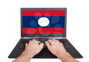 Hands working on laptop showing on the screen the flag of Laos