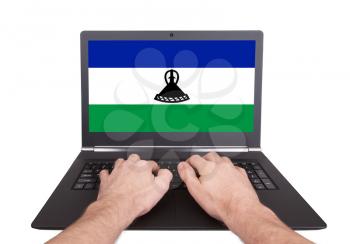 Hands working on laptop showing on the screen the flag of Lesotho