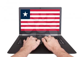 Hands working on laptop showing on the screen the flag of Liberia