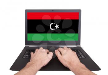 Hands working on laptop showing on the screen the flag of Libya