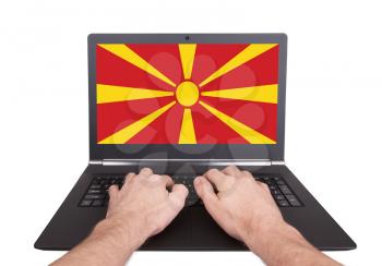Hands working on laptop showing on the screen the flag of Macedonia