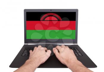 Hands working on laptop showing on the screen the flag of Malawi