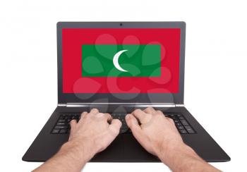 Hands working on laptop showing on the screen the flag of Maldives