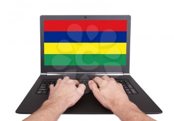 Hands working on laptop showing on the screen the flag of Mauritius