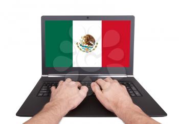 Hands working on laptop showing on the screen the flag of Mexico