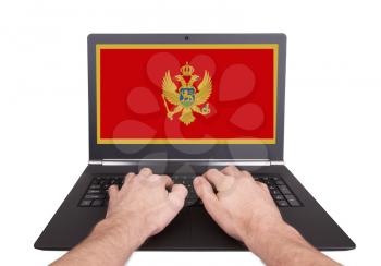 Hands working on laptop showing on the screen the flag of Montenegro