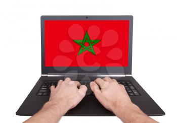 Hands working on laptop showing on the screen the flag of Morocco
