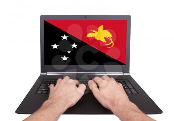 Hands working on laptop showing on the screen the flag of Papua New Guinea