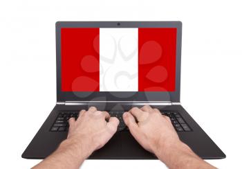 Hands working on laptop showing on the screen the flag of Peru