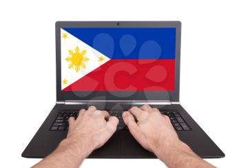 Hands working on laptop showing on the screen the flag of Philippines