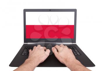 Hands working on laptop showing on the screen the flag of Poland