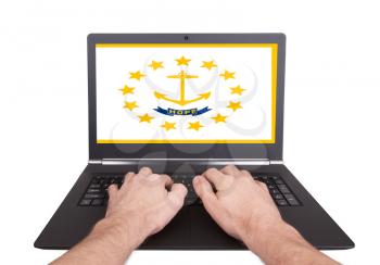 Hands working on laptop showing on the screen the flag of Rhode Island
