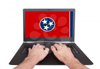 Hands working on laptop showing on the screen the flag of Tennessee