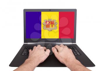 Hands working on laptop showing on the screen the flag of Andorra