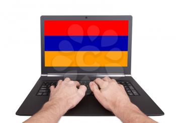 Hands working on laptop showing on the screen the flag of Armenia