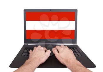 Hands working on laptop showing on the screen the flag of Austria