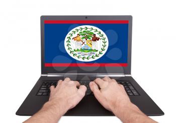 Hands working on laptop showing on the screen the flag of Belize