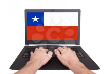 Hands working on laptop showing on the screen the flag of Chile