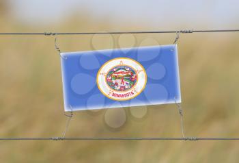Border fence - Old plastic sign with a flag - Minnesota