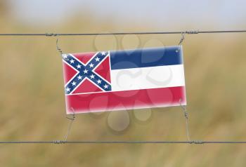 Border fence - Old plastic sign with a flag - Mississippi