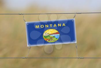 Border fence - Old plastic sign with a flag - Montana