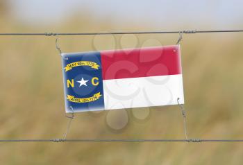 Border fence - Old plastic sign with a flag - North Carolina