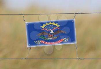 Border fence - Old plastic sign with a flag - North Dakota