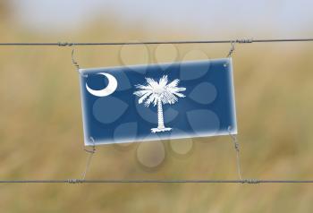 Border fence - Old plastic sign with a flag - South Carolina