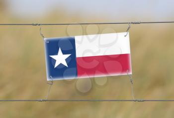 Border fence - Old plastic sign with a flag - Texas