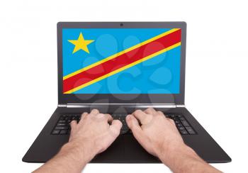 Hands working on laptop showing on the screen the flag of Conga
